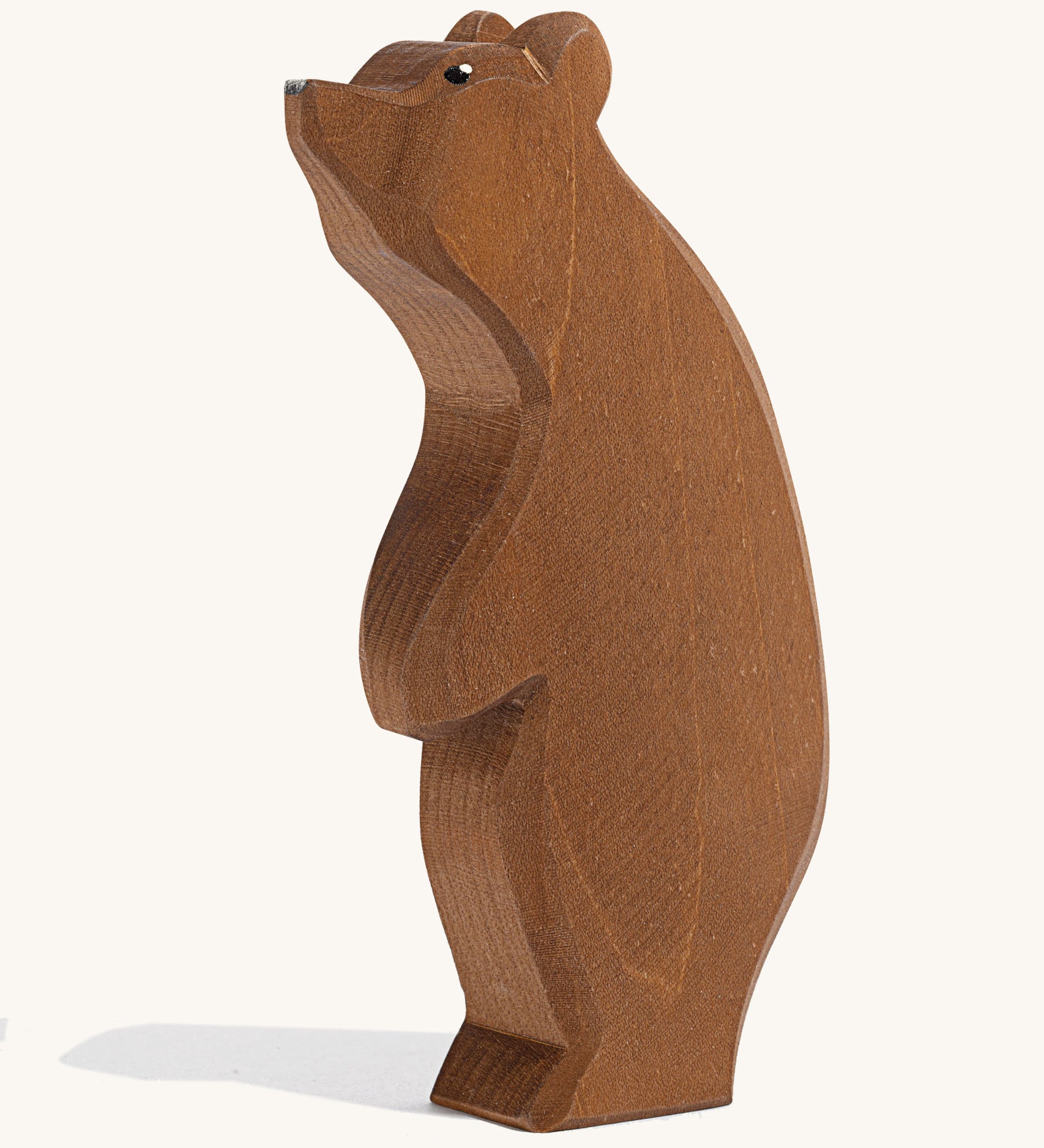 A wooden Ostheimer large brown bear standing with its head high on a cream background.