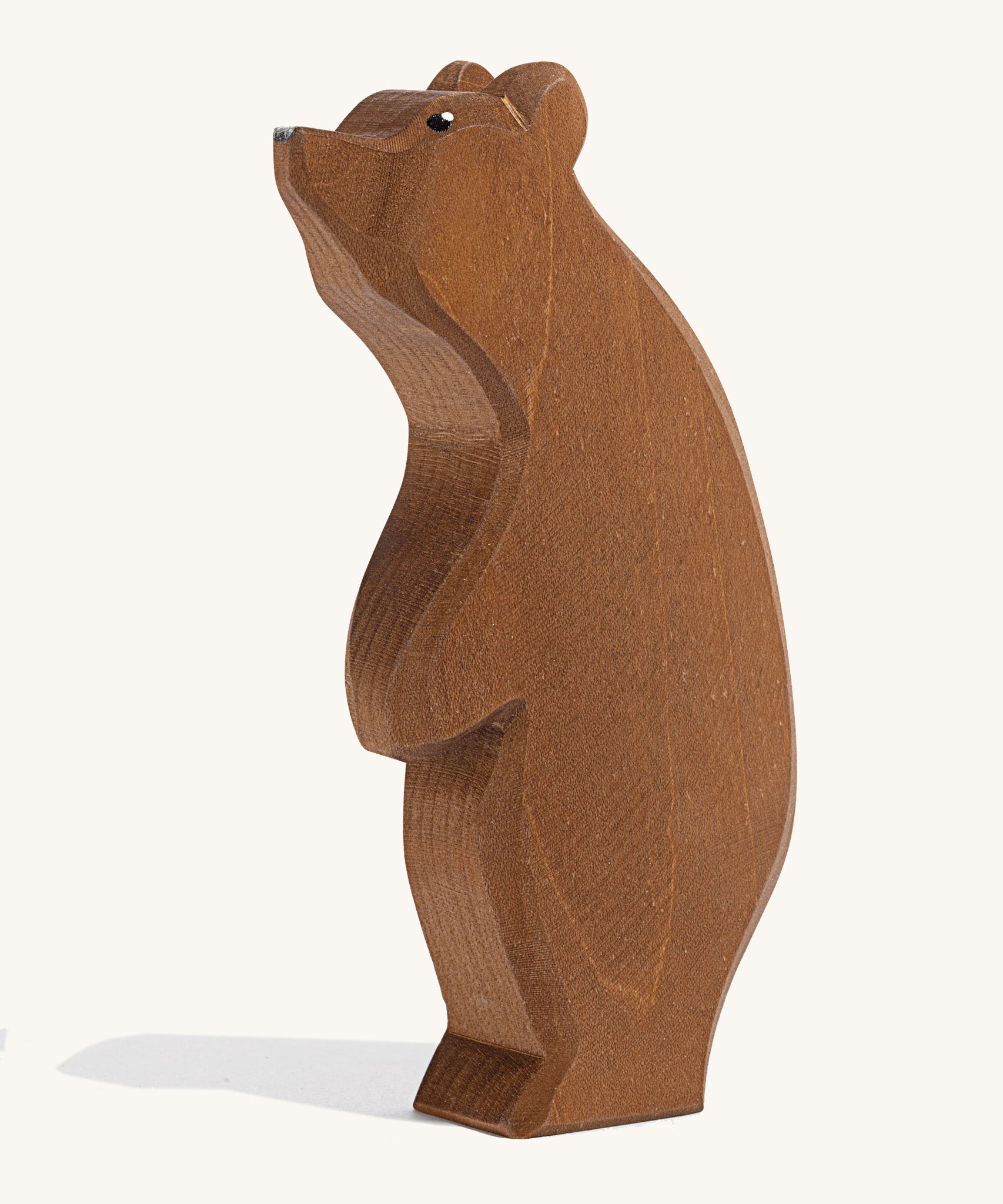 A wooden Ostheimer large brown bear standing with its head high on a cream background.