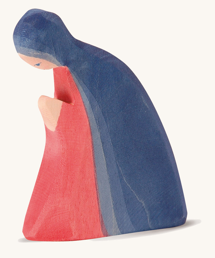 A wooden Ostheimer Mary figure wearing a red gown and blue cape on a cream background.