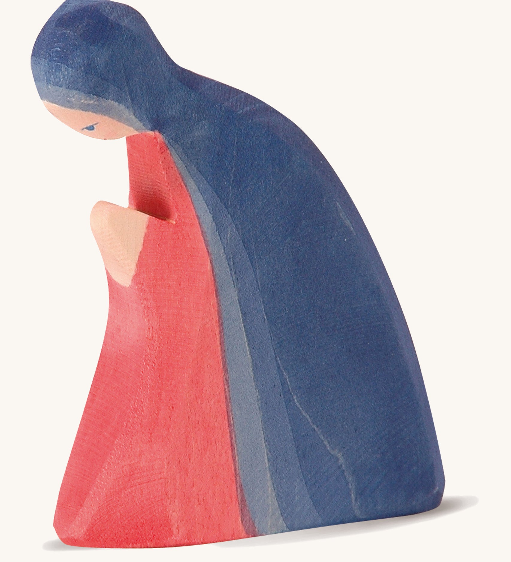 A wooden Ostheimer Mary figure wearing a red gown and blue cape on a cream background.