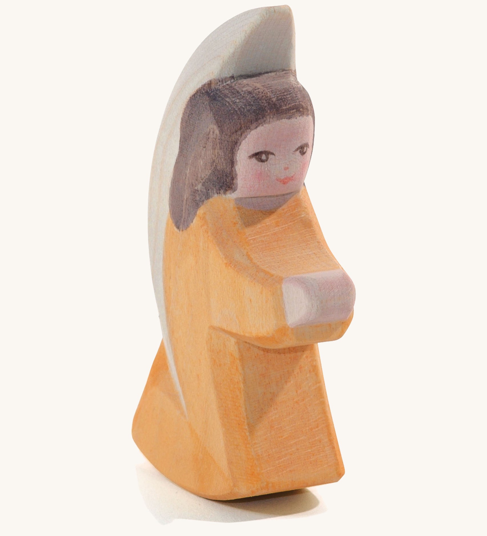 A wooden orange Ostheimer little angel figure on a cream background.