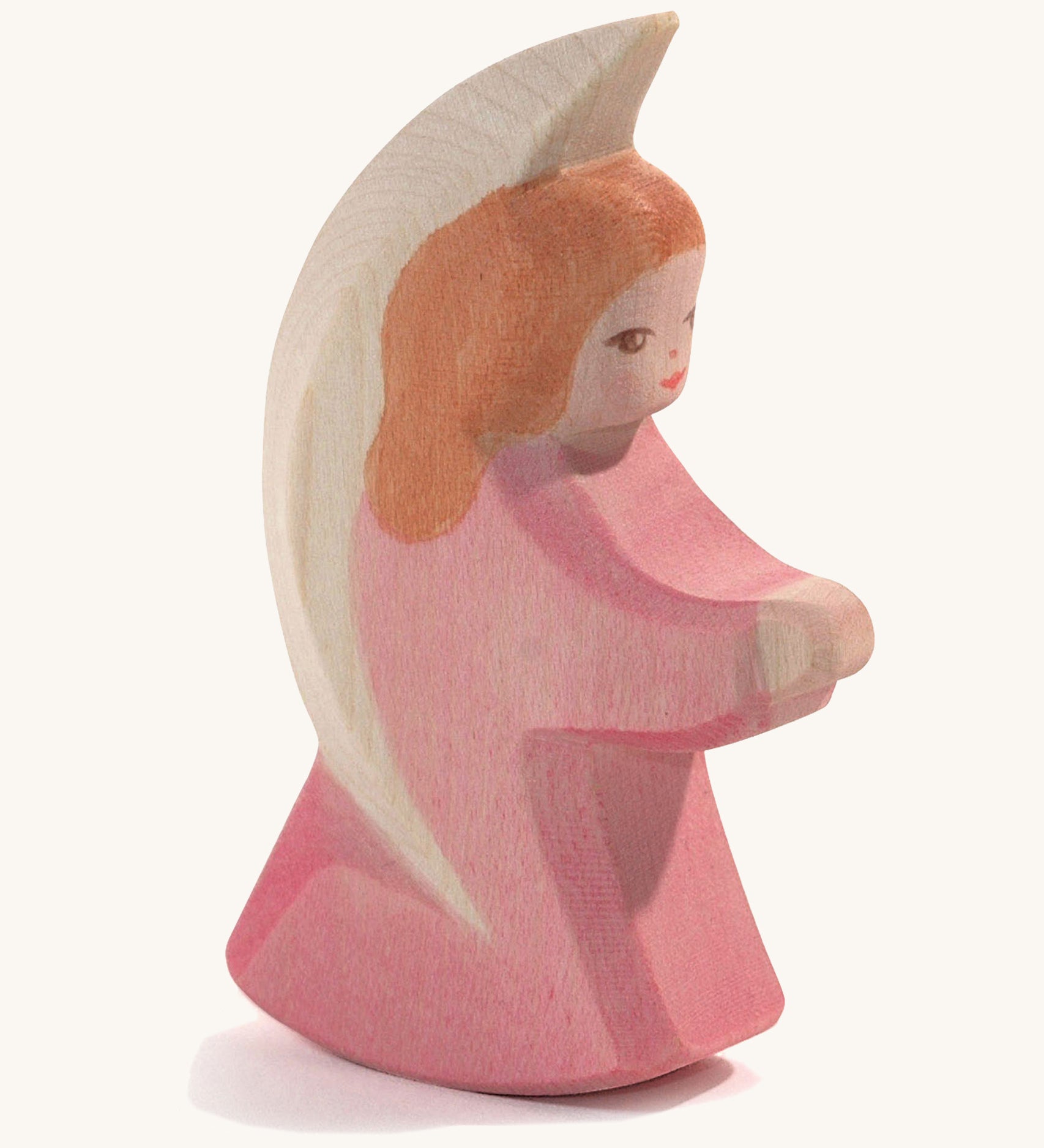 A wooden pink Ostheimer little angel figure on a cream background.