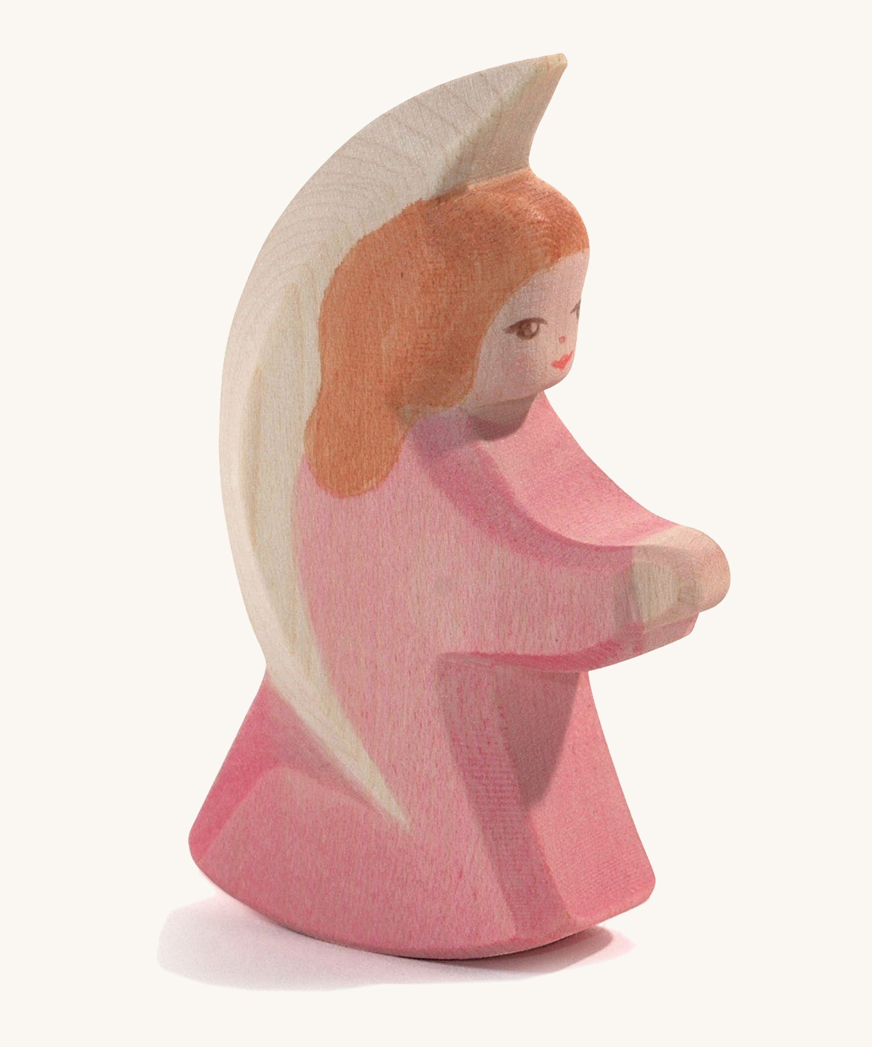 A wooden pink Ostheimer little angel figure on a cream background.