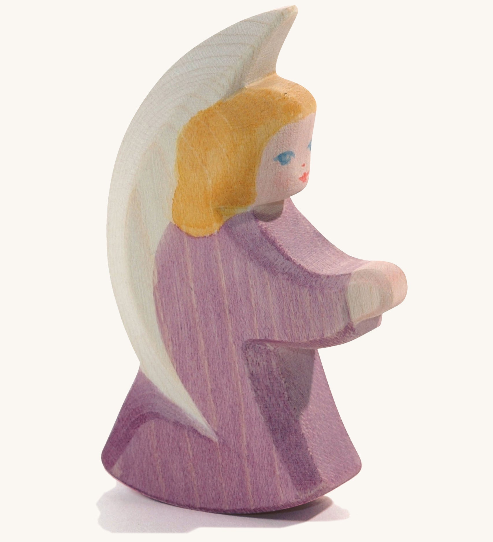 A wooden purple Ostheimer little angel figure on a cream background.