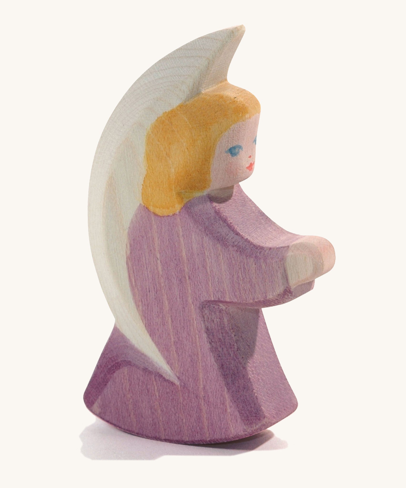 A wooden purple Ostheimer little angel figure on a cream background.