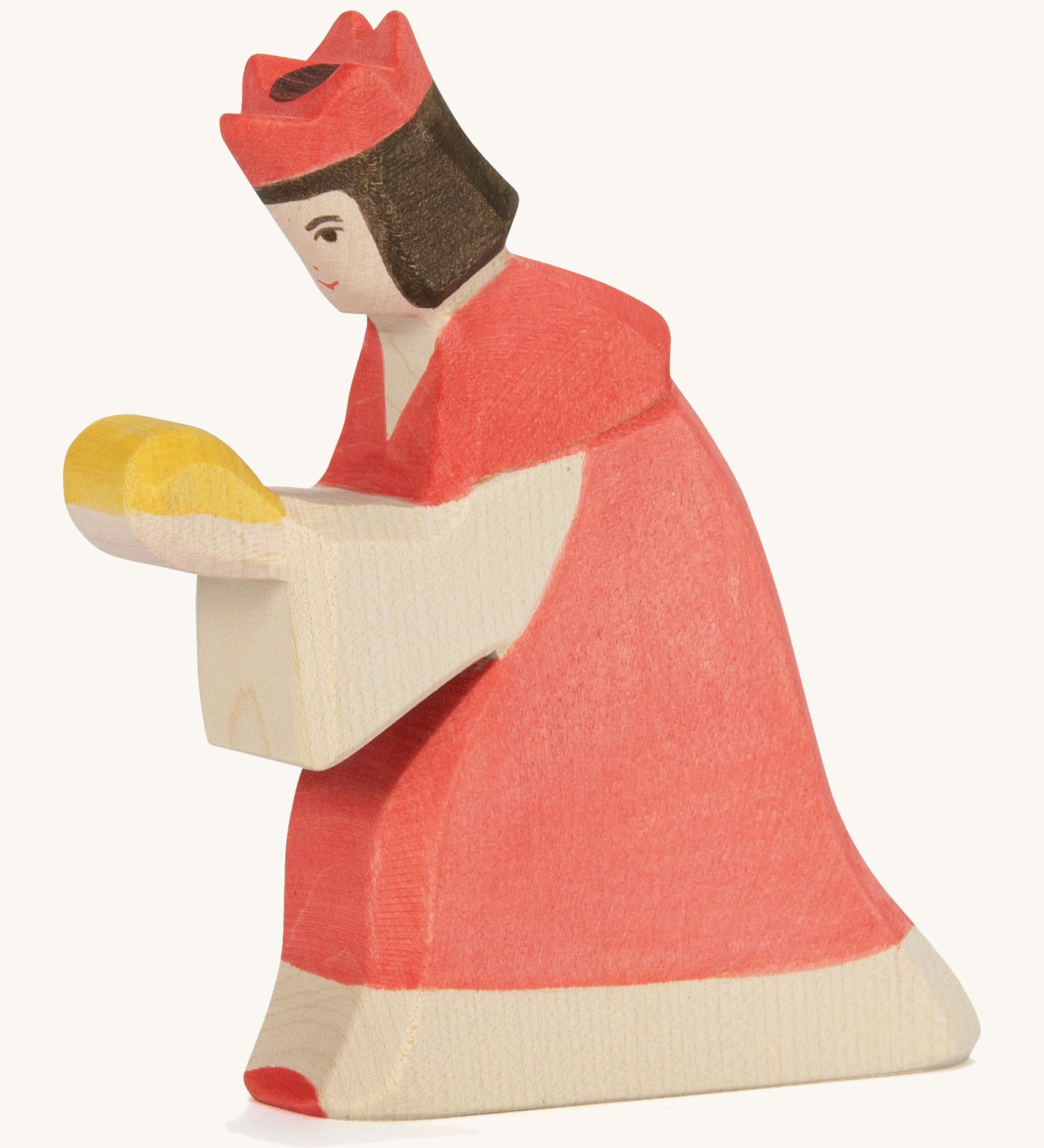 A Ostheimer wooden king figure wearing a red gown and a red crown on his head on a cream background.