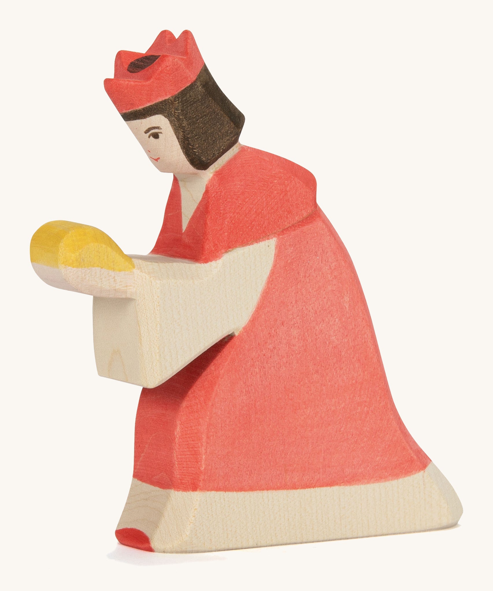 A Ostheimer wooden king figure wearing a red gown and a red crown on his head on a cream background.