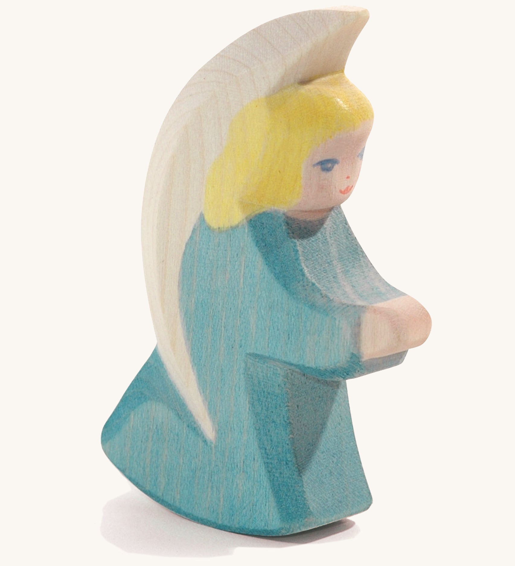 A wooden turquoise Ostheimer little angel figure on a cream background.