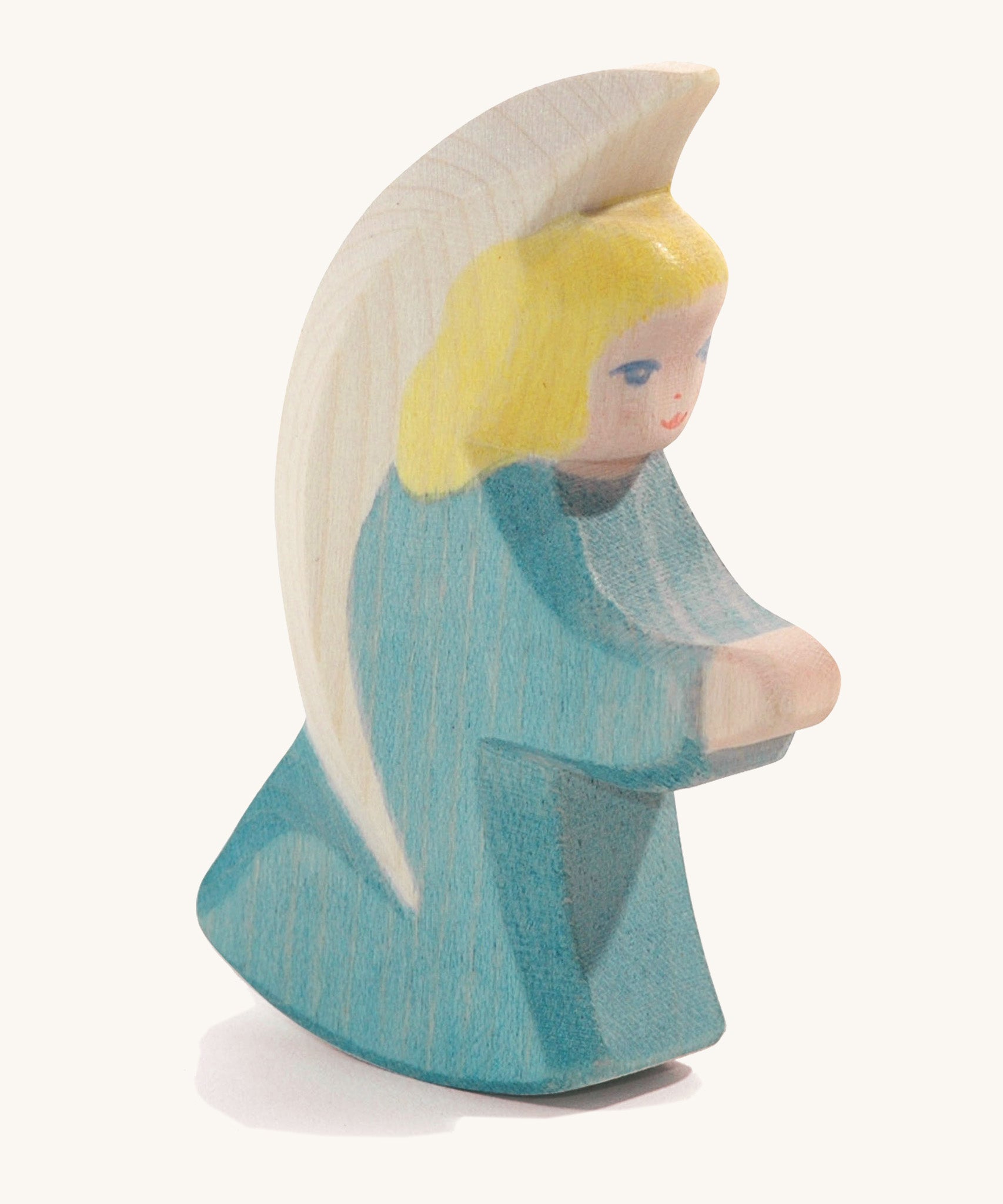 A wooden turquoise Ostheimer little angel figure on a cream background.