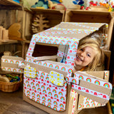 Child sitting in a car made out of cardboard. The car is decorated in Babipur paper tape. The photo has been taken in a playroom.