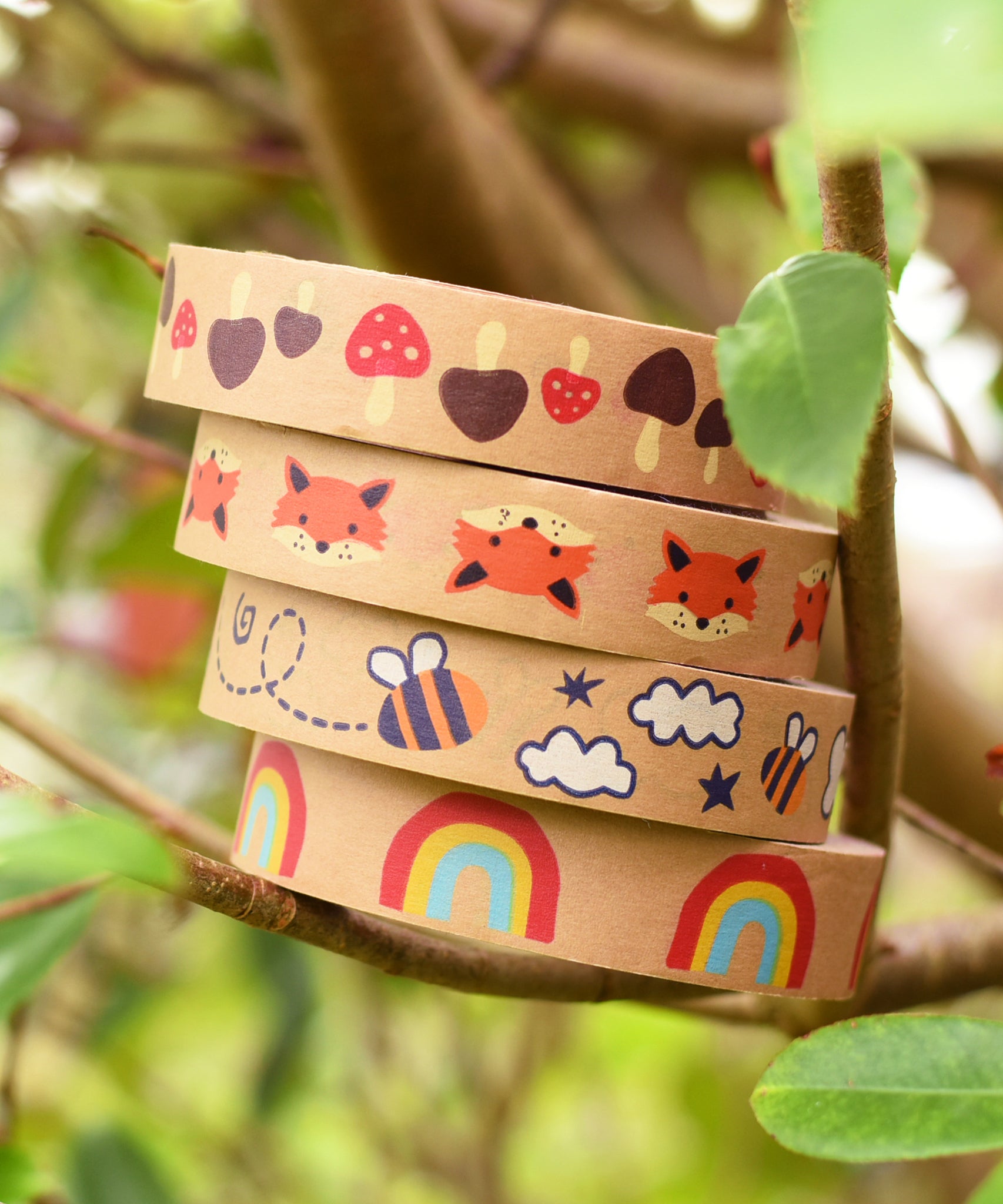 A stack of Babipur Kraft Eco Paper Tape including Mushroom, Fox, Bee and Rainbow, in an outdoor setting