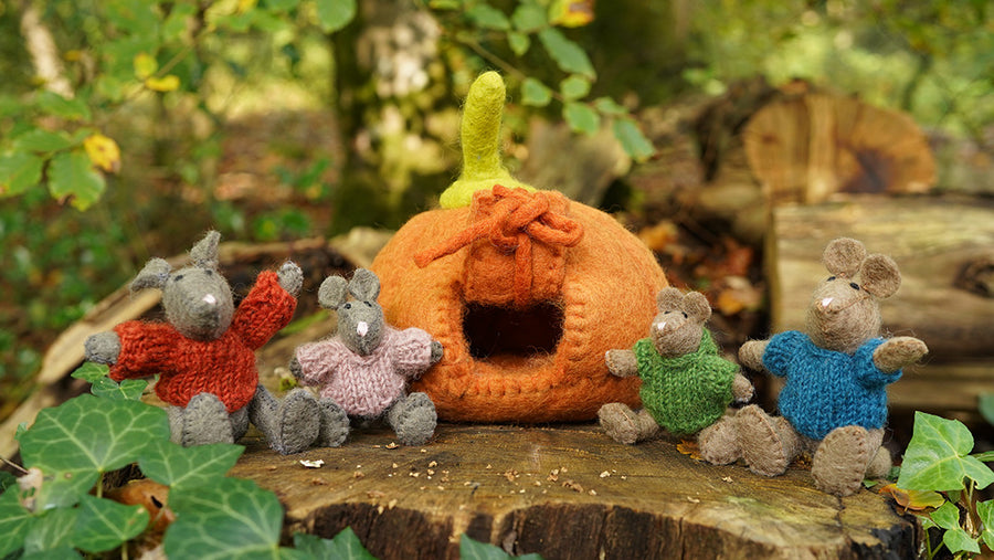 A wool mouse family by Papoose Toys with a wool pumpkin, surrounded by a woodland background