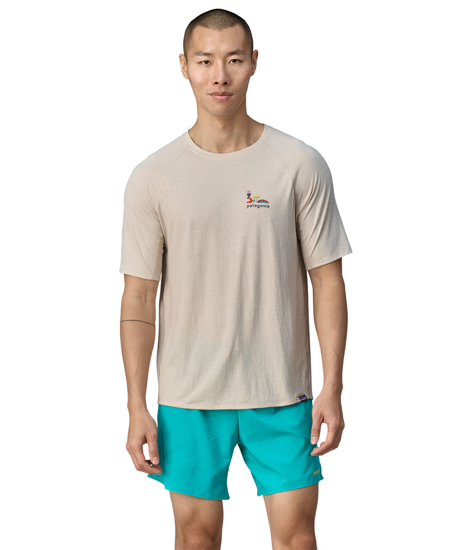 A person wearing light blue shorts, is wearing the Patagonia Men's Cap Cool Trail Graphic T-Shirt to show the fit from the front