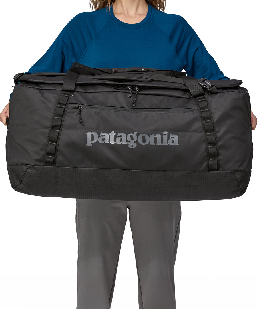 A person holding the Patagonia Black Hole Duffel 100L Black in their hands to show the size