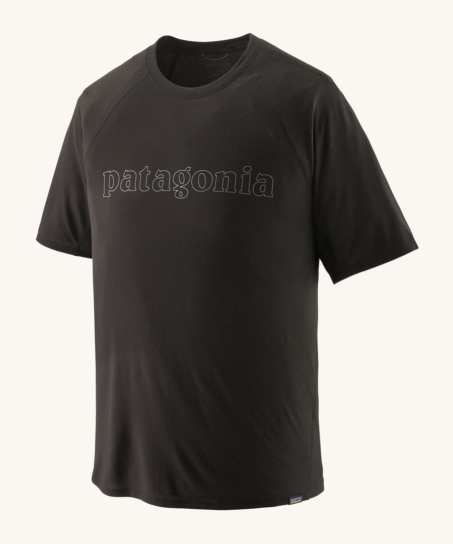 The Patagonia Men's Cap Cool Trail Graphic T-Shirt - Black. An organic cotton, adult t-shirt in black, with lack textured Patagonia text on the front of the top. On a plain background