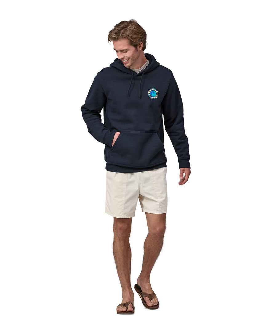 An adult wearing the Patagonia Unity Fitz Uprisal Hoody - New Navy, with white shorts. Perfect for keeping warm