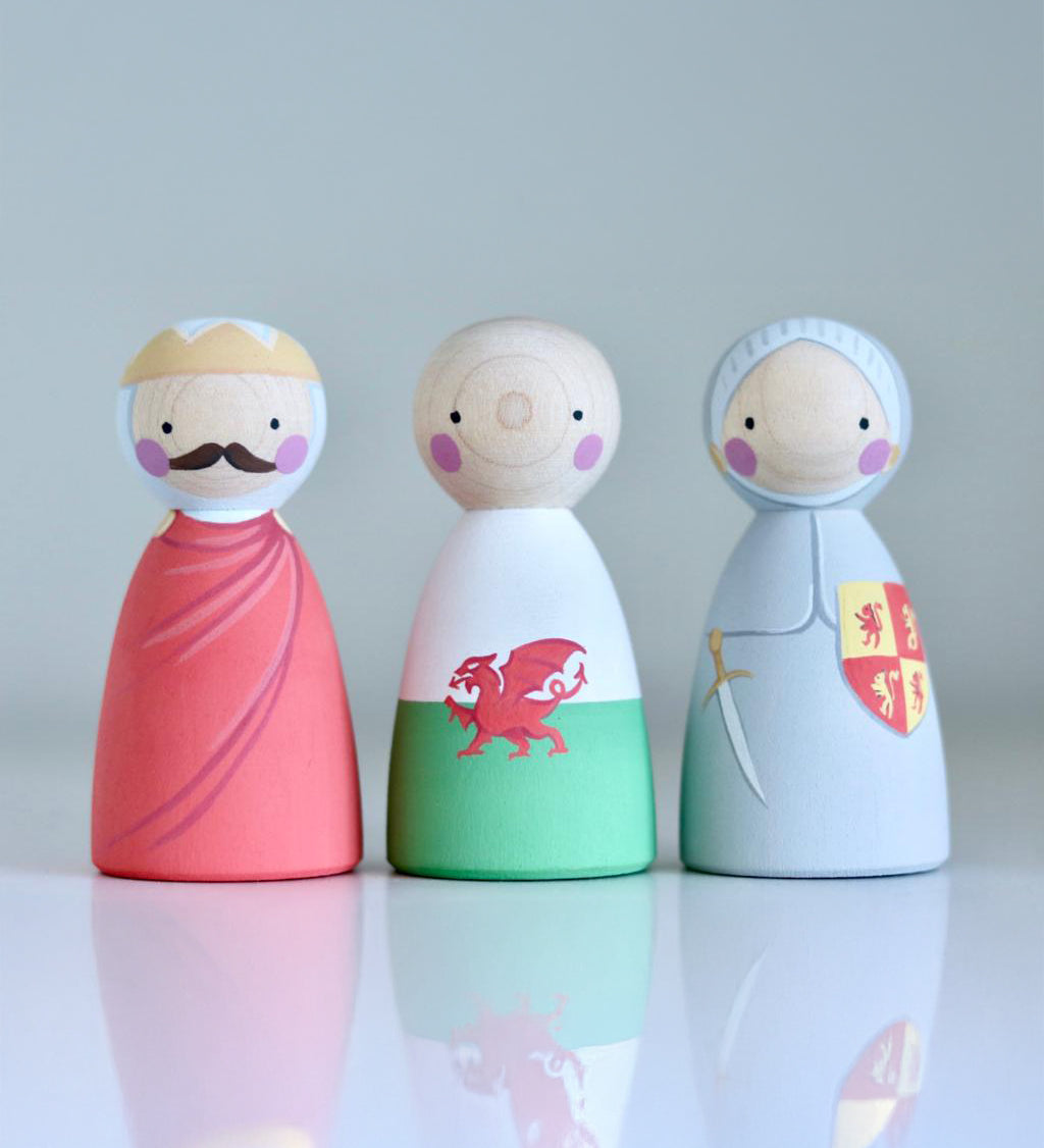 The People Llywelyn Fawr, Welsh Dragon and Owain Glyndwr hand painted, wooden peg dolls are on a light grey background with their reflections showing below them