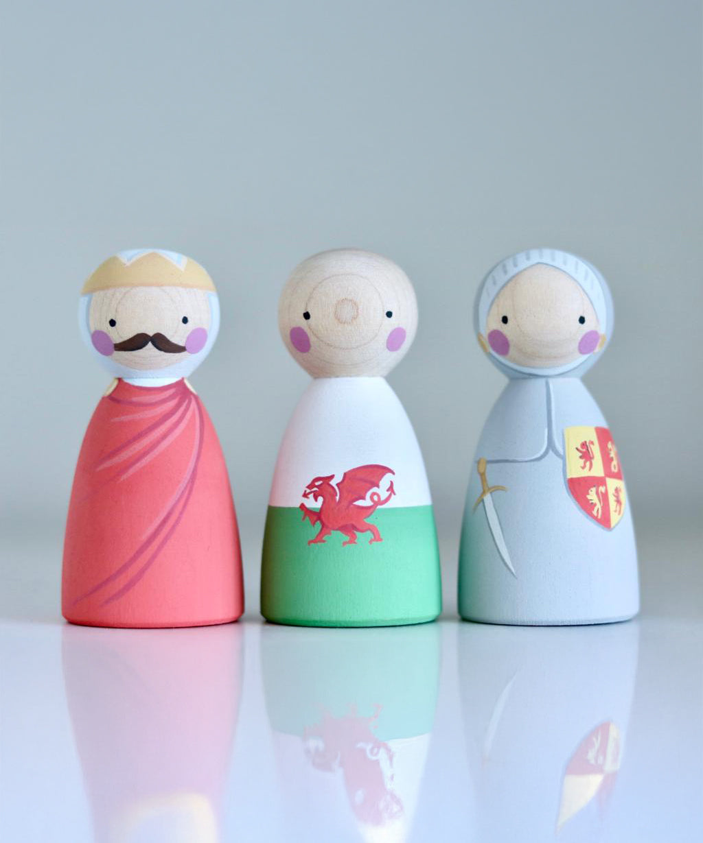 The People Llywelyn Fawr, Welsh Dragon and Owain Glyndwr hand painted, wooden peg dolls are on a light grey background with their reflections showing below them