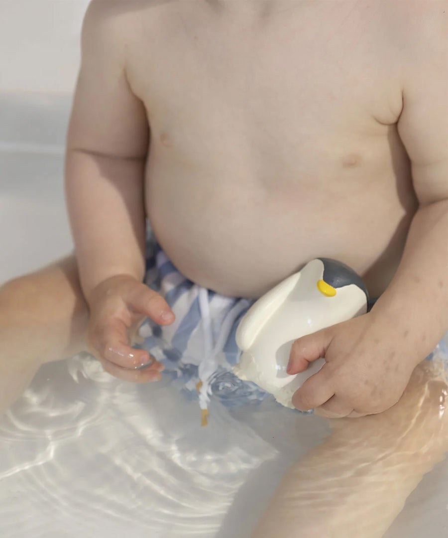 A child playing with the Oli &amp; Carol Penguin Bath Toy in a bath