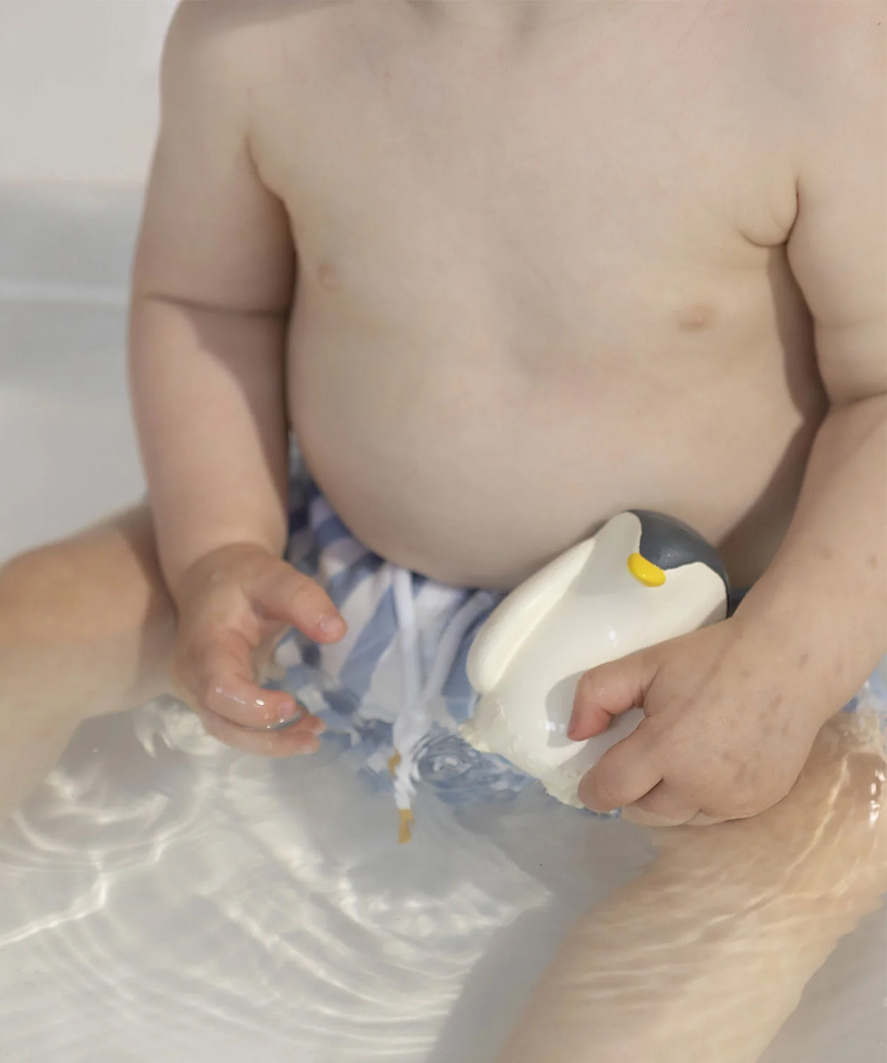 A child playing with the Oli &amp; Carol Penguin Bath Toy in a bath