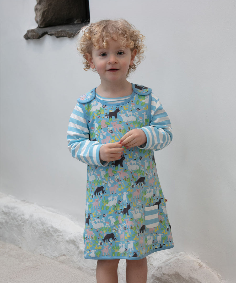 A child wearing the Piccalilly Country Friends Reversible Dress, showing the farm yard animal print