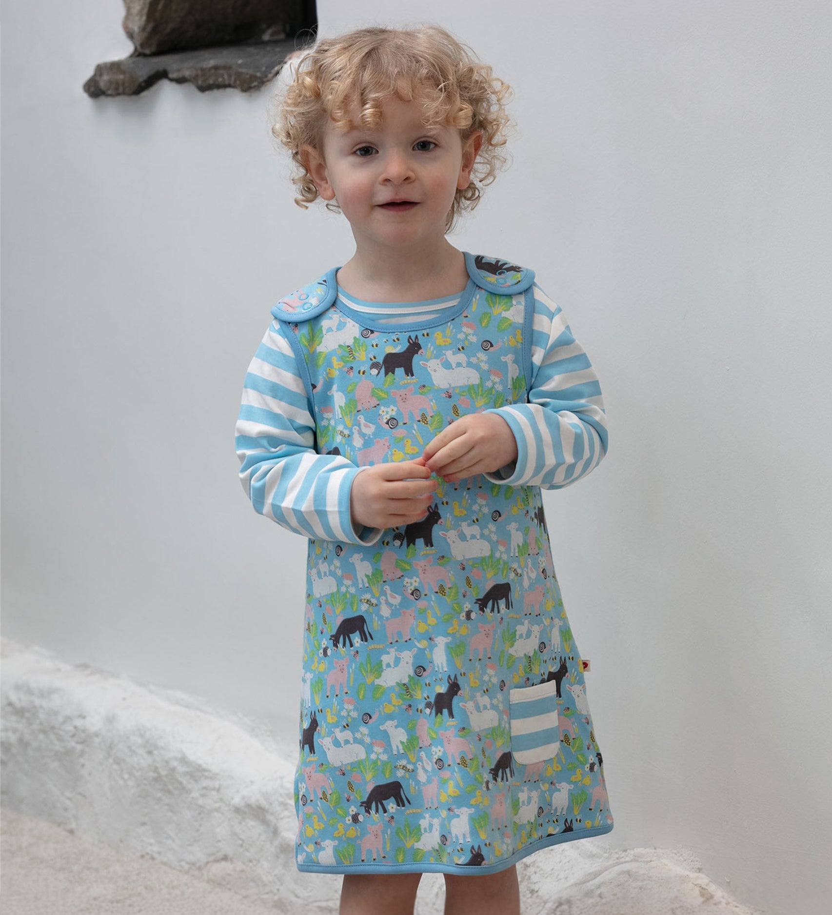 A child wearing the Piccalilly Country Friends Reversible Dress, showing the farm yard animal print