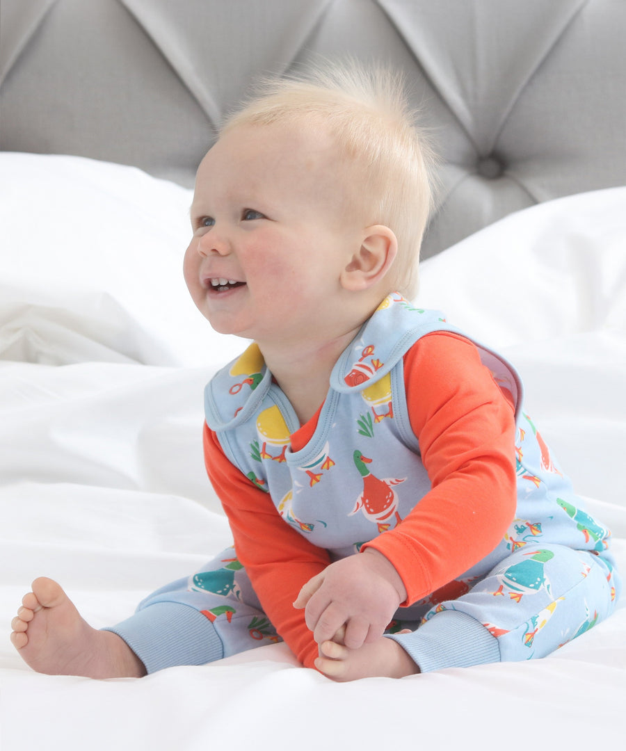 A child happily wearing the Piccalilly Duck Days Dungarees