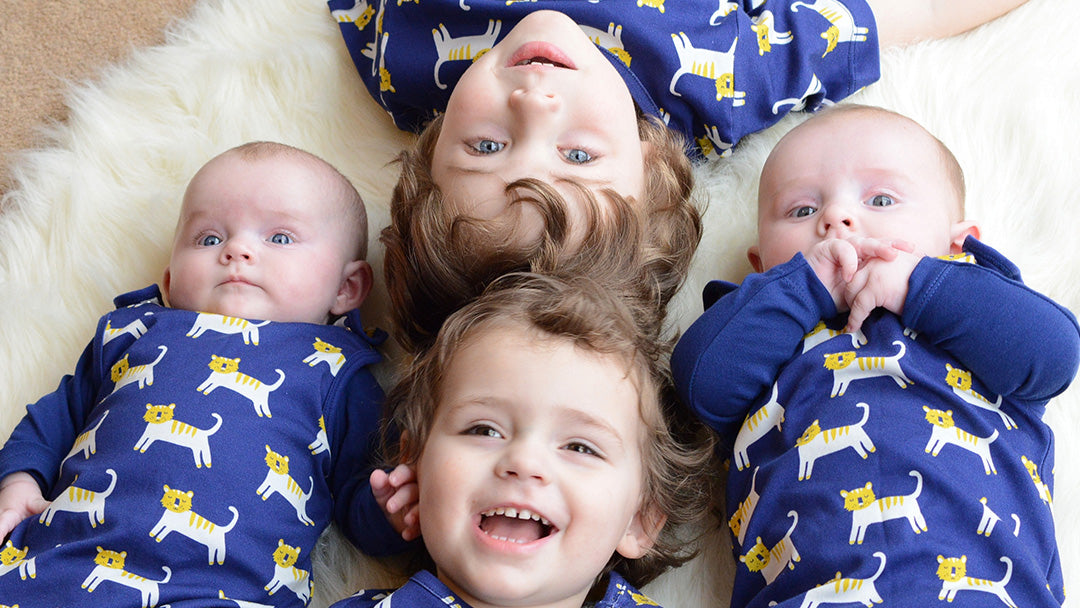 Two children and two babies wearing matching Piccalilly organic outfits