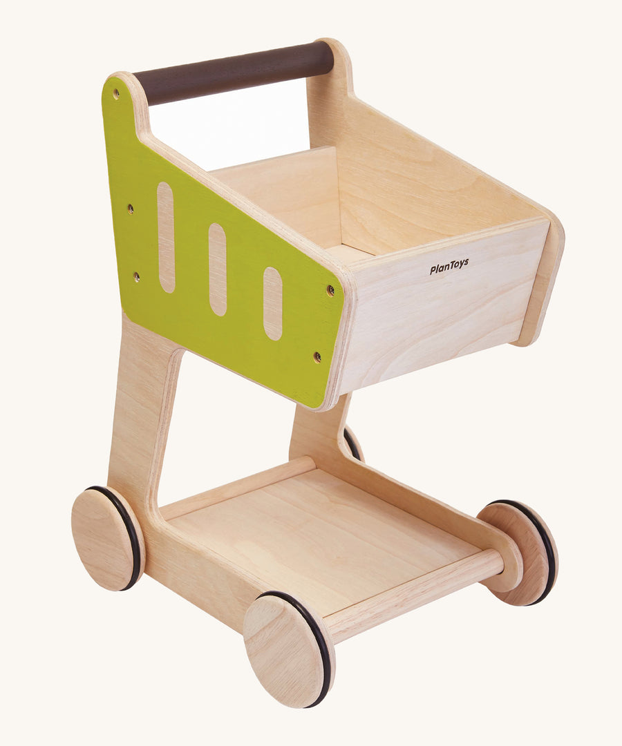 PlanToys Shopping Trolley is a fun, wooden kid size trolley with green sides and a brown handle. This trollwy is fun for storing play food and can also e used in shopping role play.  The image is on a cream background