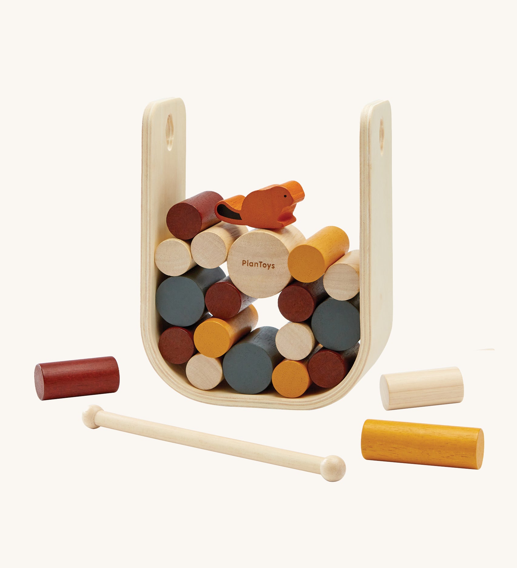 The PlanToys Giant Beaver Tumble is a fun kids game of strategic thinking and hand-eye coordination, using the wooden stick to push out the logs without the beaver falling. There is a large natural wood U shaped base to keep the sticks and beaver upright, and the sticks are in various sizes and colours such as yellow, brown, white and grey. The little beaver piece is orange with a black tal. The image is on a cream background.