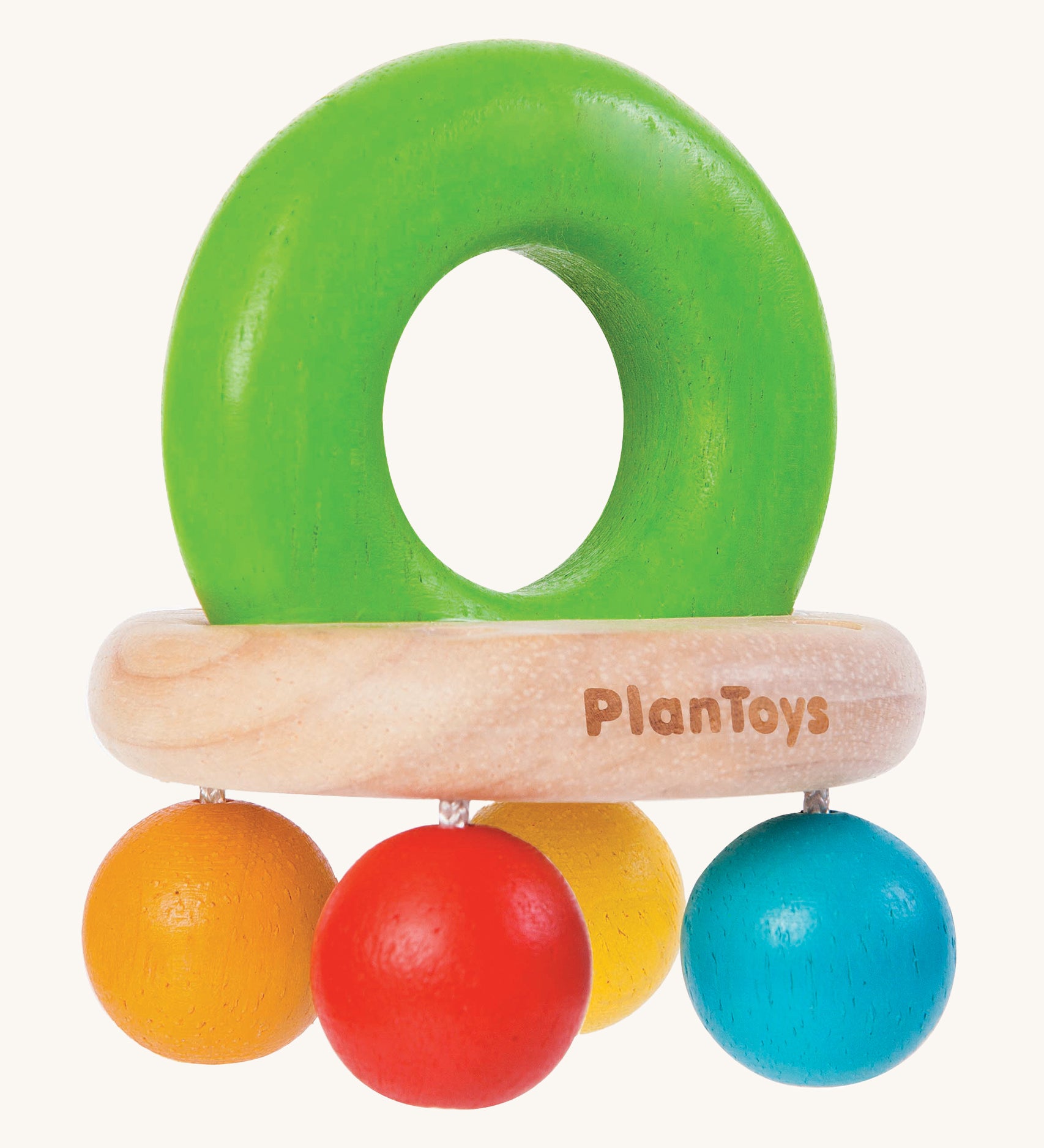 PlanToys Bell Rattle, is a beautiful wooden baby toy. The rattle comes in the shape of a bell, with a large green wooden ring on top for easy gripping. At the bottom of the ring is a horizontal wooden oval, and attached to the wooden oval are four bright coloured balls in blue, orange, red and yellow. The image is on a cream background