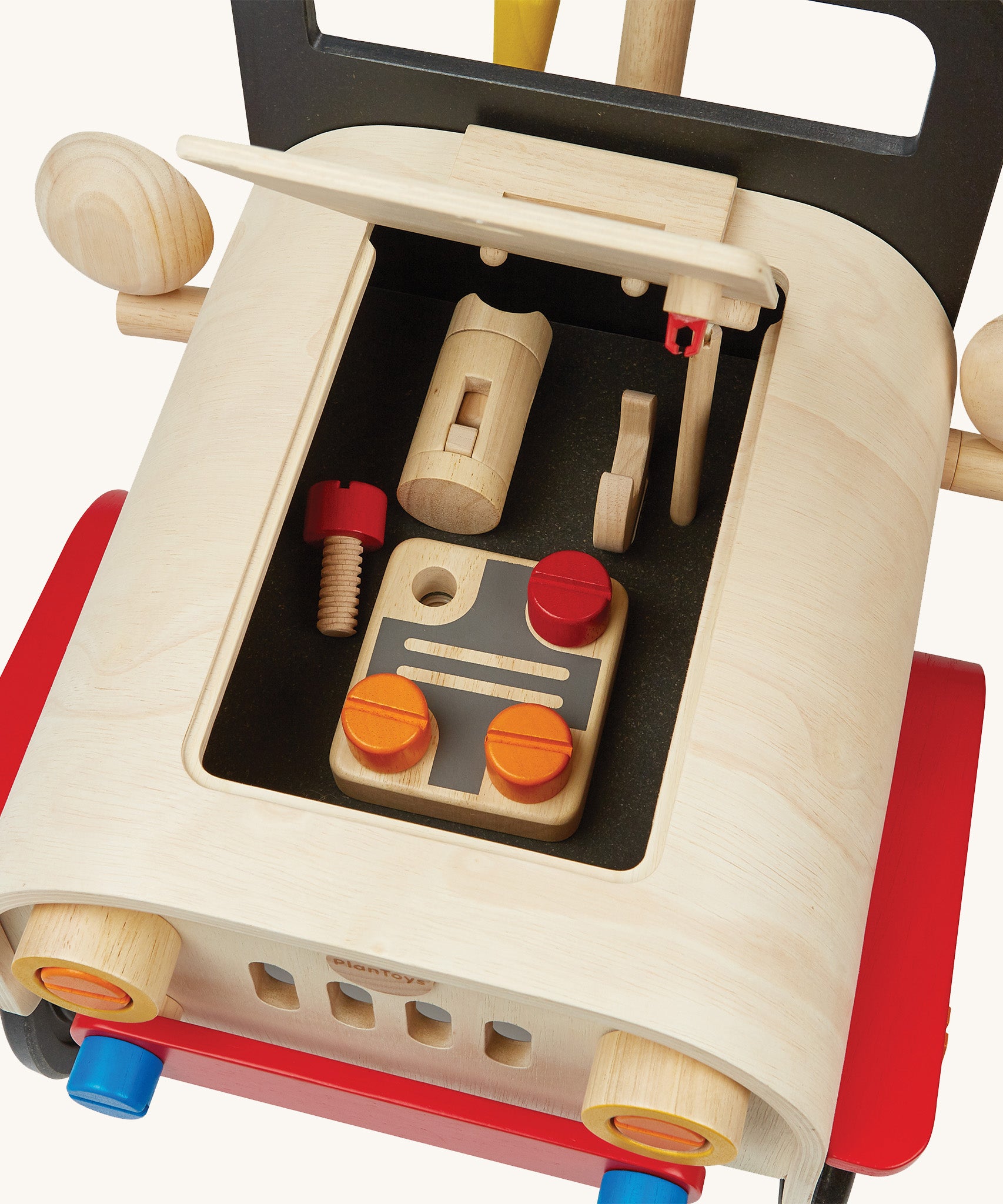 The wooden engine and tools inside the bonnet of the PlanToys Motor Mechanic on a cream background