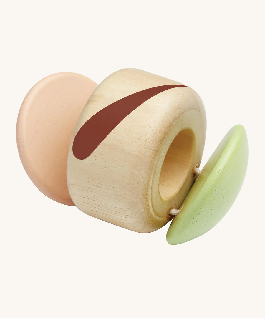 The PlanToys plastic-free, wooden clapping roller toy is a fun, sensory toy for babies and little ones. The clapper sides are in a soft pink and soft green colour, an the middle is natural wood with a brown stripe. The image is on a cream background.