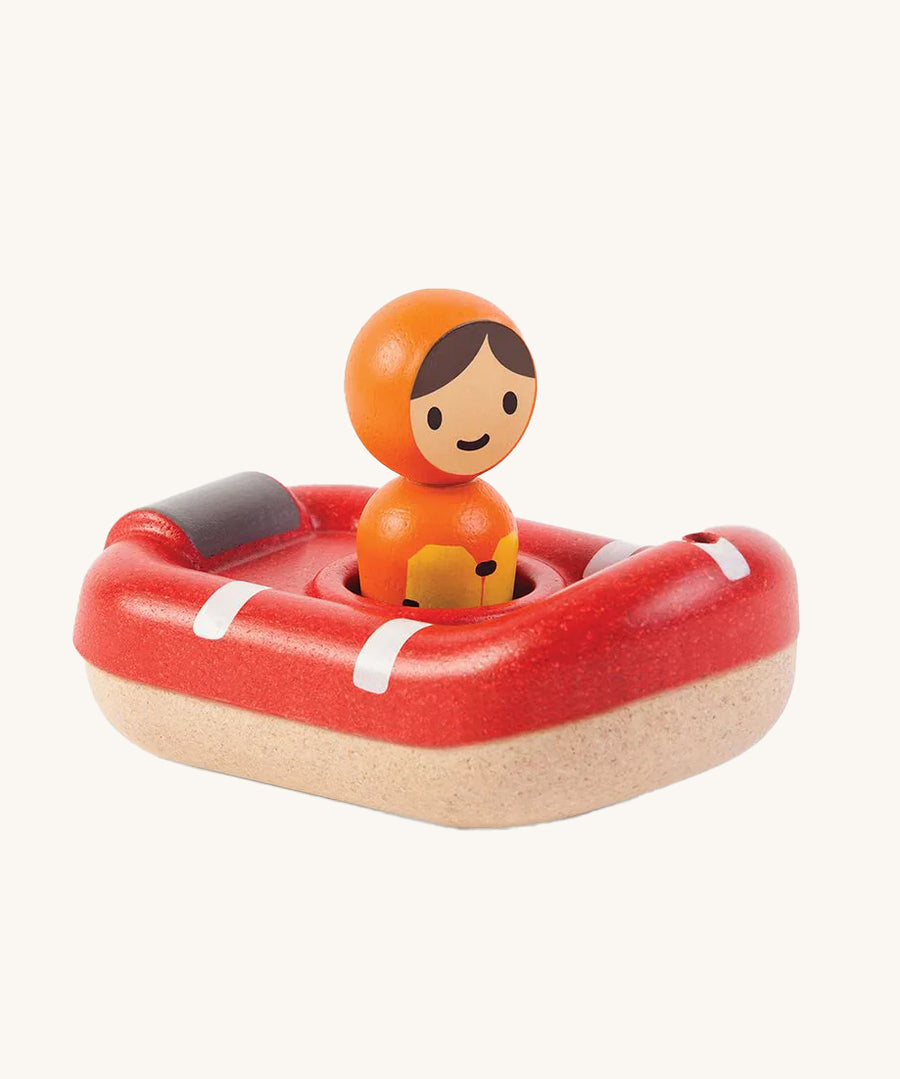 PlanToys Coast Guard Boat Bath Toy and Coastguard figure sat inside the boat, on a cream background