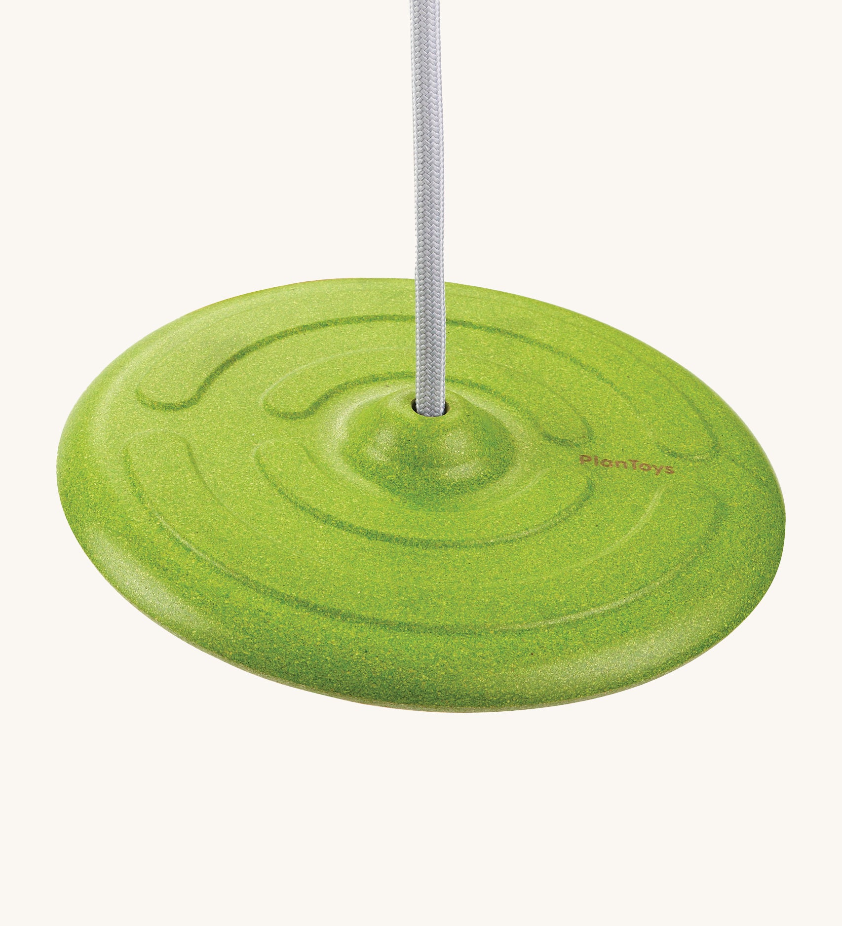 PlanToys Saucer Disc Swing in green, is an eco-friendly alternative to children's outdoor swings. This image shows a green dish shaped seat, attached to a white rope and is on a cream background