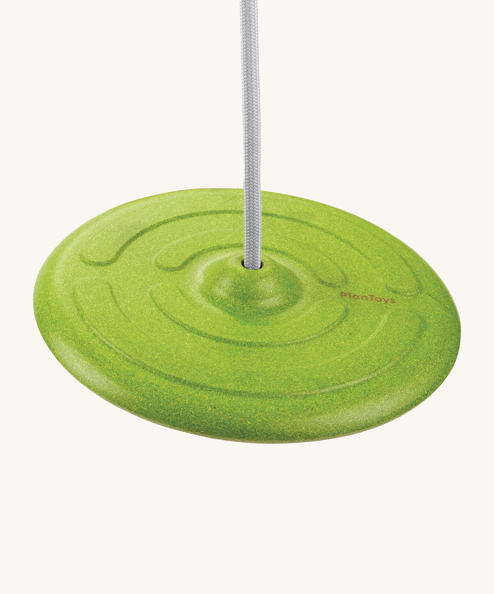 PlanToys Saucer Disc Swing in green, is an eco-friendly alternative to children's outdoor swings. This image shows a green dish shaped seat, attached to a white rope and is on a cream background