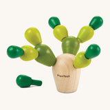 The PlanToys Mini Balancing Cactus with a natural wooden block where the green coloured pegs go into, to create a cactus shaped toy. The image is on a cream background