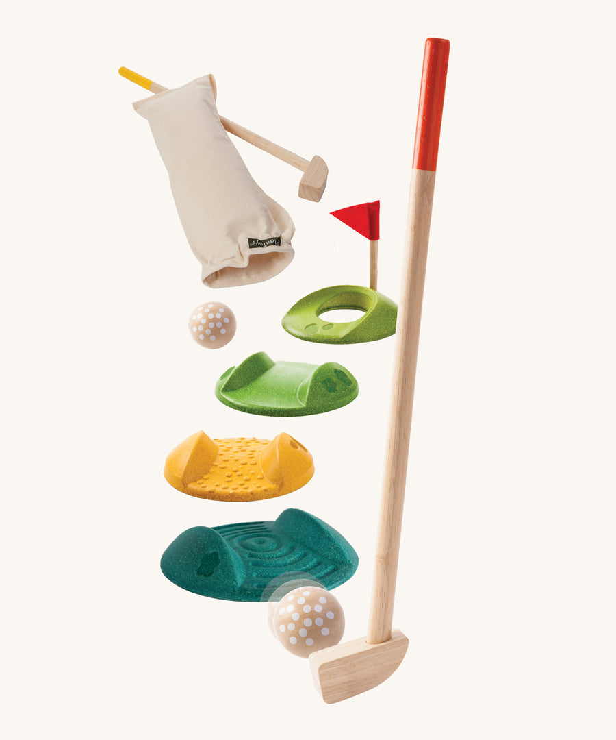 The PlanToys Mini Golf Game is a fun and sensory set, which Includes 2 wooden kids-sized golf clubs, 3 challenge tracks, 2 balls, 1 hole and a handy bag. Each track piece has a different texture on the top. The image is on a cream backgorund