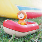 The PlanToys Coast Guard Boat Bath Toy laid on a grassy floor and being played with outside