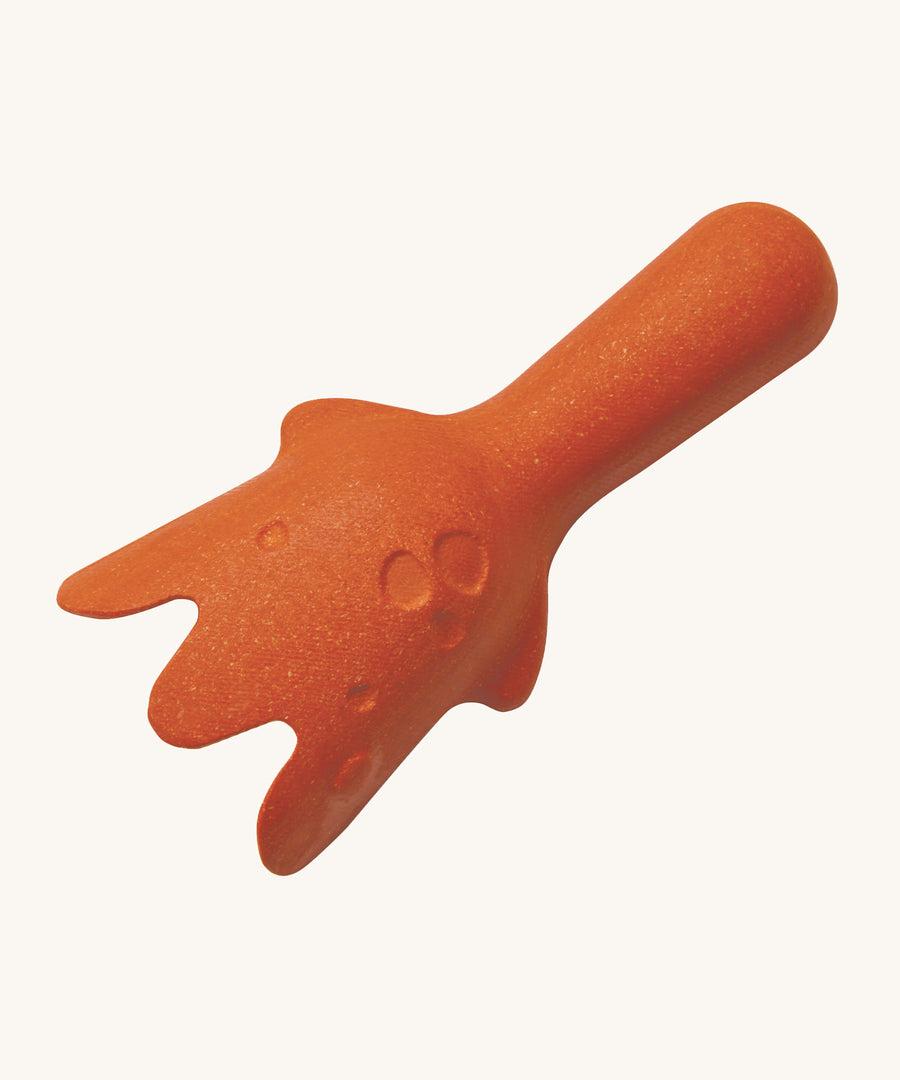 The back of the orange scooper from the PlanToys Sand Play Set, which has raised and indented circles to look like the rocks in the ocean