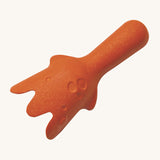 The back of the orange scooper from the PlanToys Sand Play Set, which has raised and indented circles to look like the rocks in the ocean