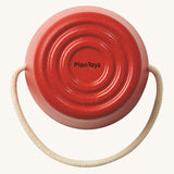 The base of the Plan Toys red bucket from the Sand Play Set showing the beige rope handle and the circle pattern base on the bottom