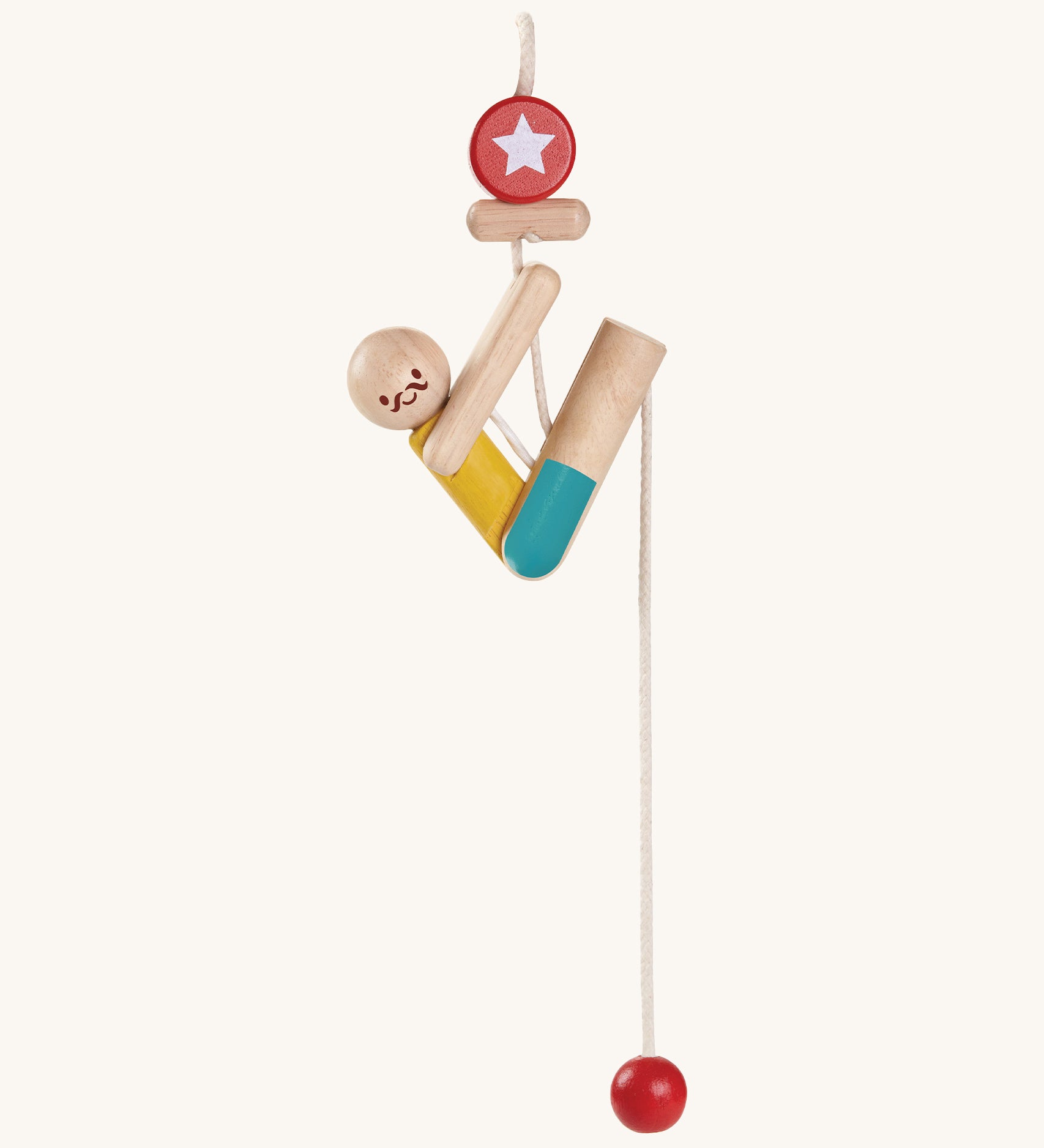 The PlanToys Rope Climbing Acrobat is a fun little wooden figure, on a rope. The acrobat is made fron natural wood pieces, and has a yellow painted top and blue painted shorts. There s a red circle with a star at the top of the rope, and a red ball at the bottom. The image is on a cream background