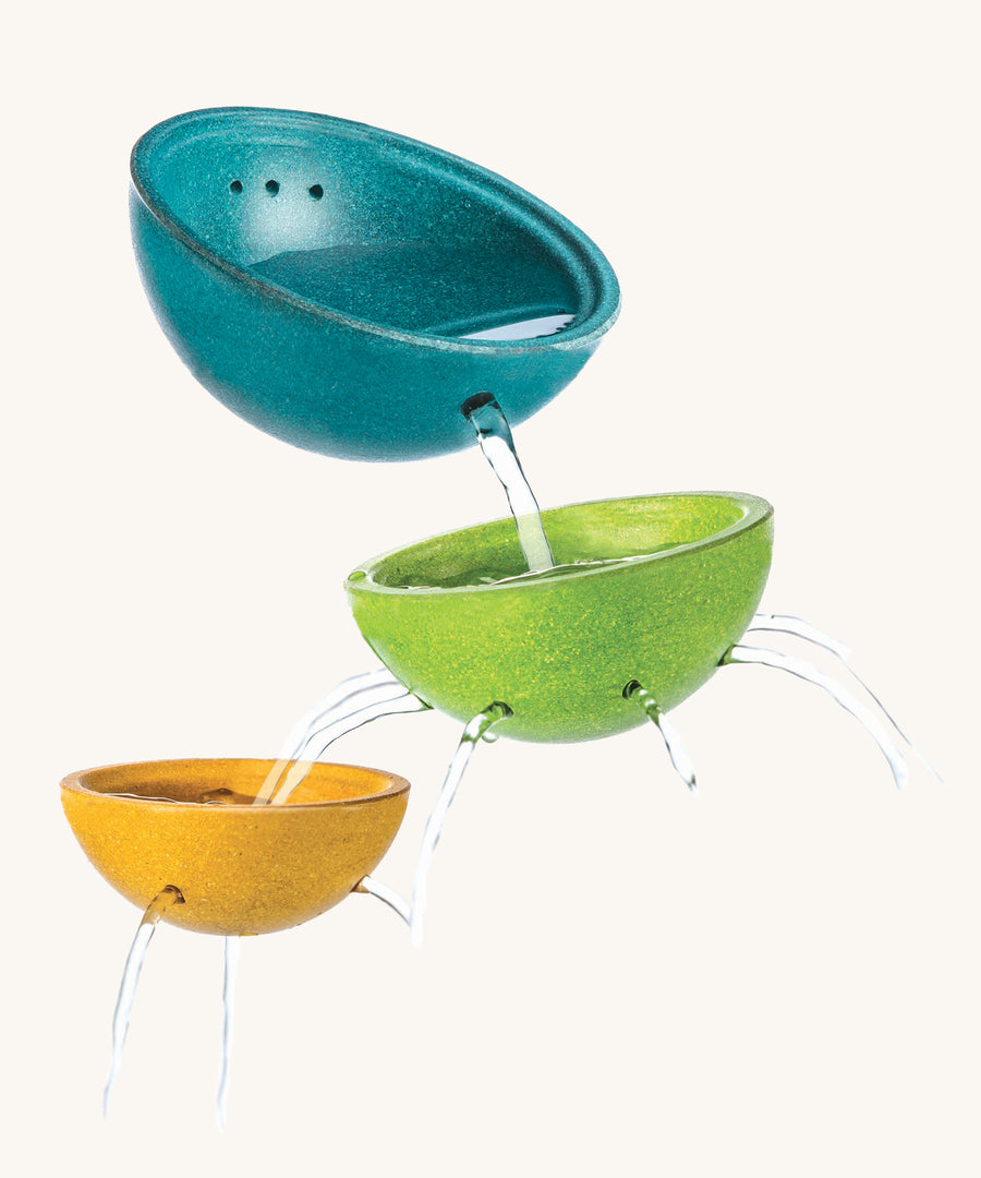 PlanToys Fountain Bowl Set, has three bowls made from PlanWood (a recycled rubber wood made by PlanToys). The bowls are blue, green and yellow, and have holes in the side and bottom to allow water to flow through, for a fun sensory experience. The image is on a cream background