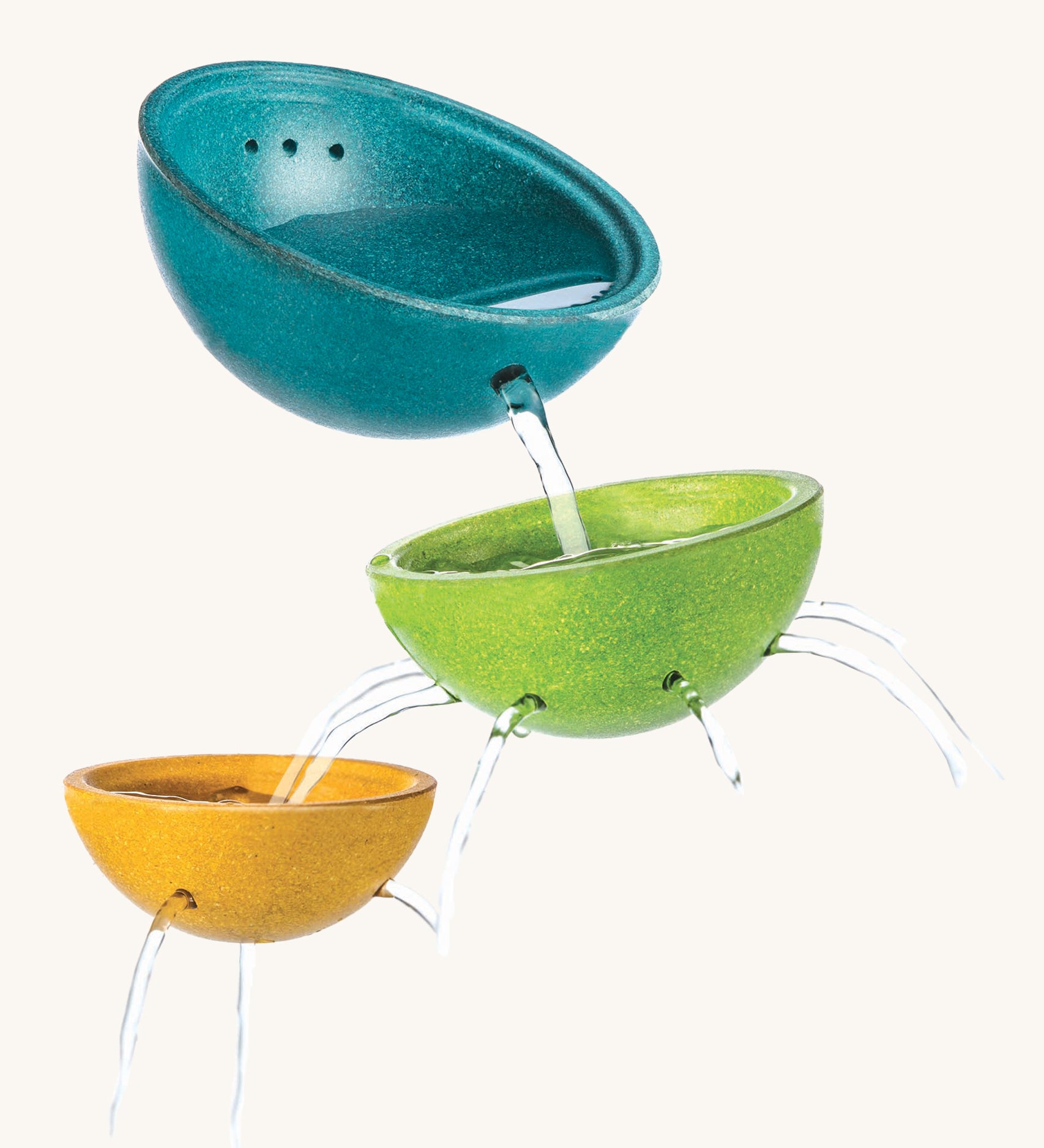 PlanToys Fountain Bowl Set, has three bowls made from PlanWood (a recycled rubber wood made by PlanToys). The bowls are blue, green and yellow, and have holes in the side and bottom to allow water to flow through, for a fun sensory experience. The image is on a cream background