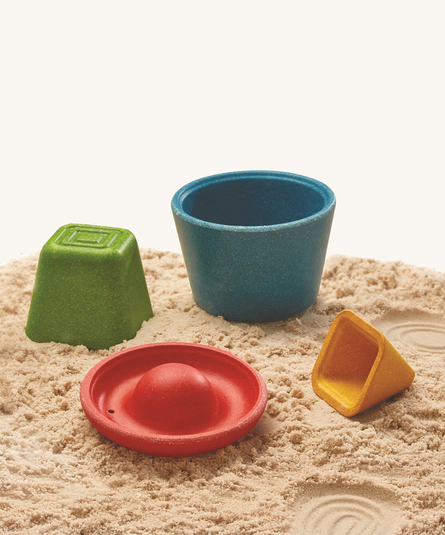 The PlanToys Creative Sand Play blocks are arranged on soft sand. Each block comes with a textured top for sensory play and to leave a textured print in the sand or mud