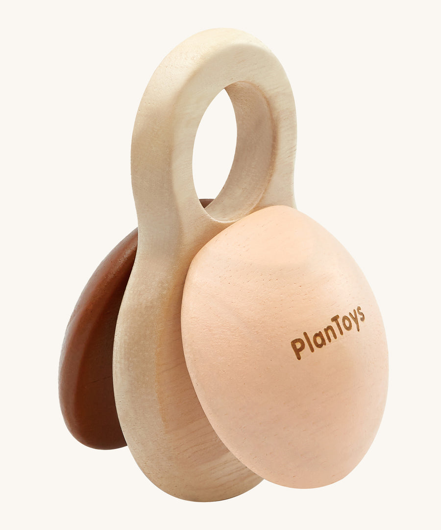 PlanToys Shake N Clap, wooden baby rattle toy offers a fun sensory experience for little ones. the clapper sides are in brown and beige, and the middle part is in natural wood with a hole in the top for easy gripping for little hands. The image is on a cream background