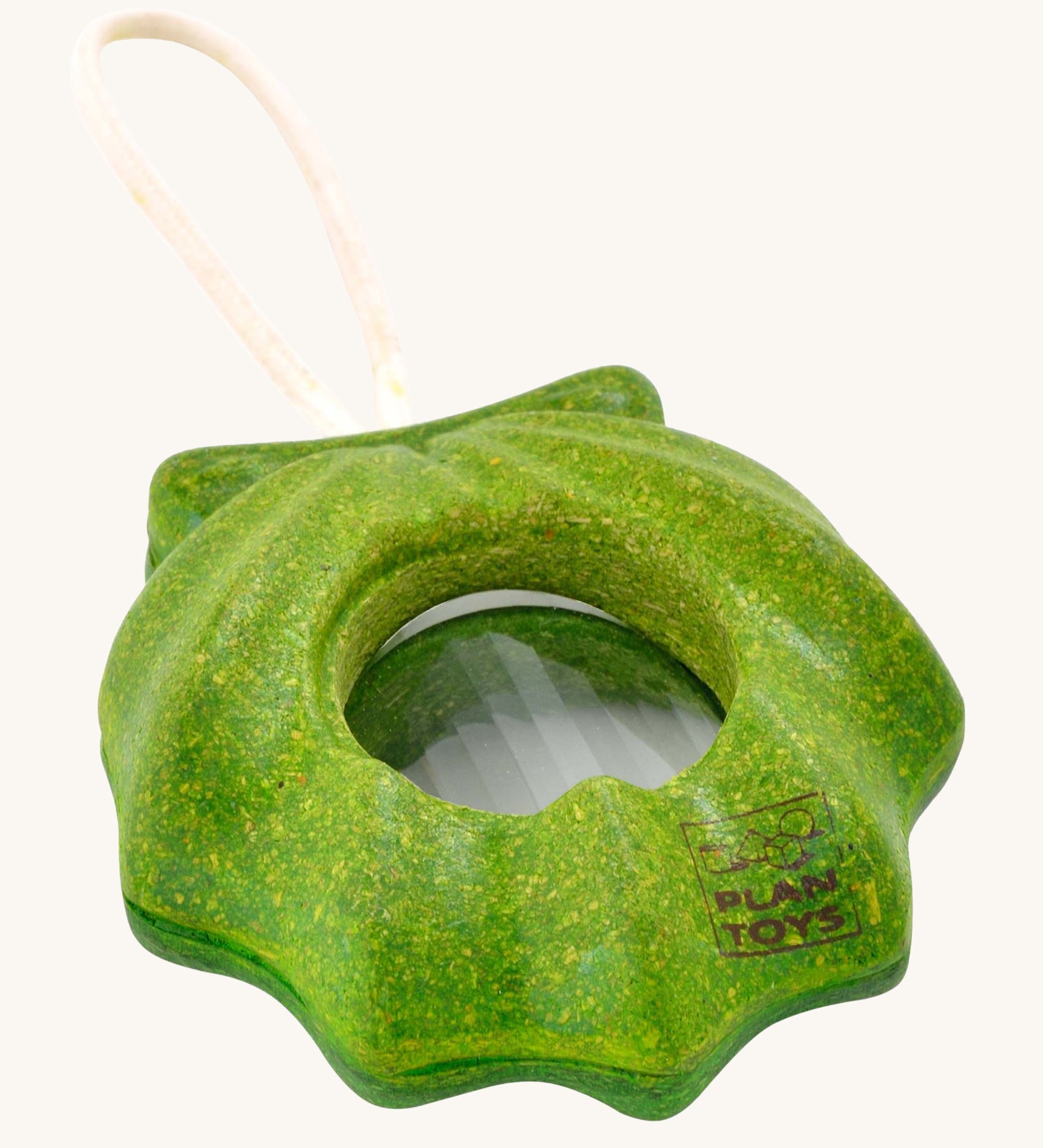 PlanToys Shell Kaleidoscope, is a green sensory kaleidoscope toy in the image of a shell, with a circular lens in the middle and a beige rope handle. The image is on a cream background 