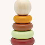 The PlanToys childrens plastic-free wooden Stacking Rings toy in the modern rustic colours on a cream background. The stakcing toy comes with a red base, a green ring, a brown ring, a yellow ring and a natural wood coloured ball on top.