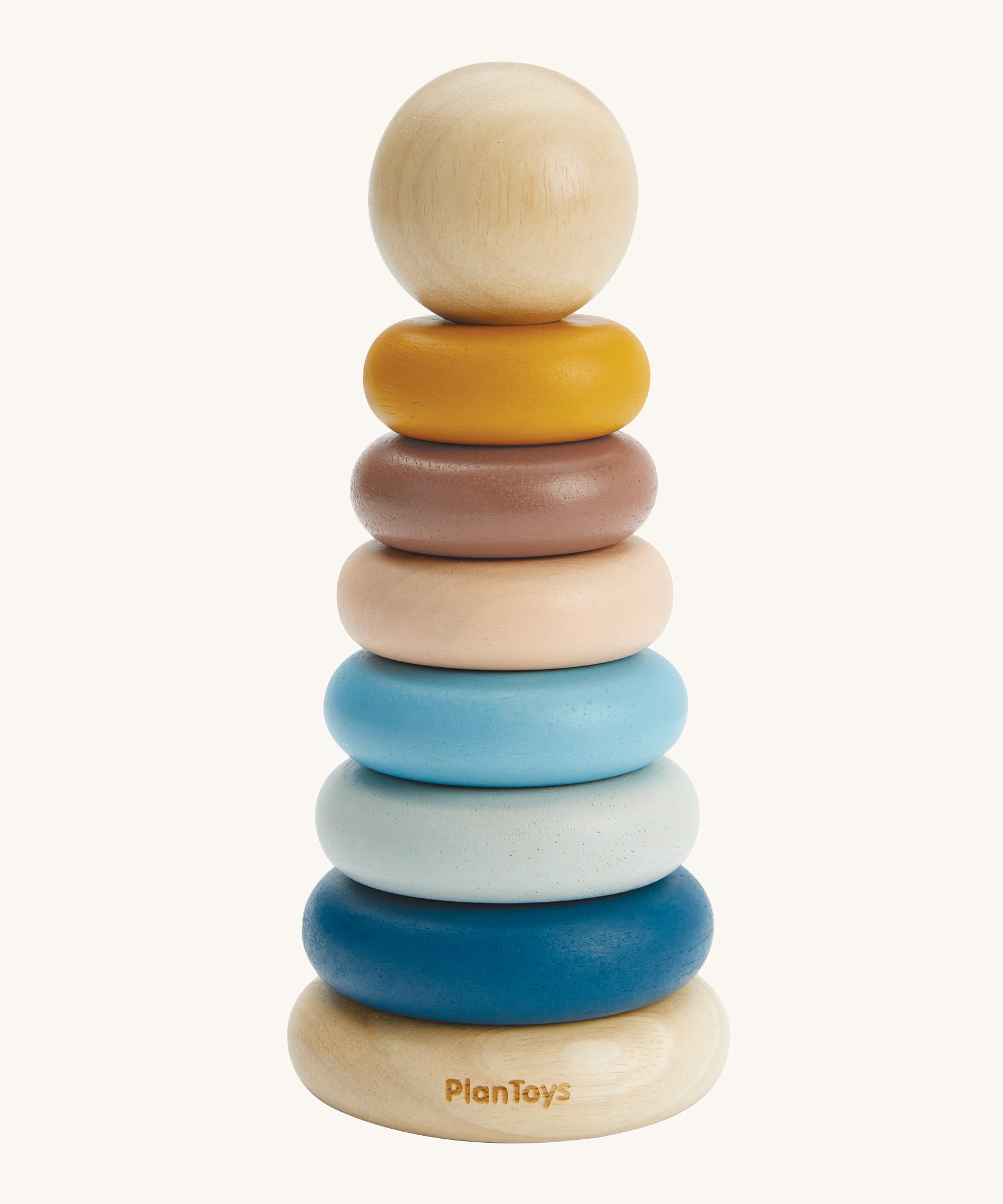 The PlanToys Stacking Rings are a fun and educational toy for children. The set comes with 6 rings in shades of blue, peach and yellow, and has a removable ball on the top that can be rolled on the ground or put inside the ring holes. The image is on a cream backround.